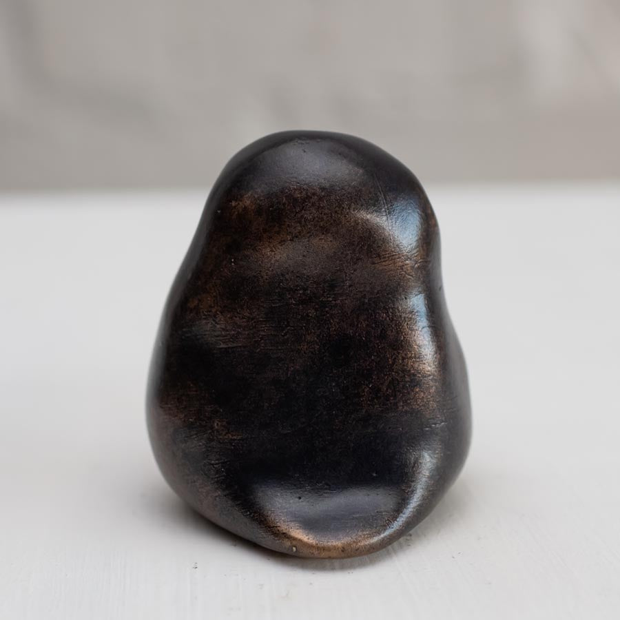 Small smooth bronze owl sculpture on a plain background - rear view