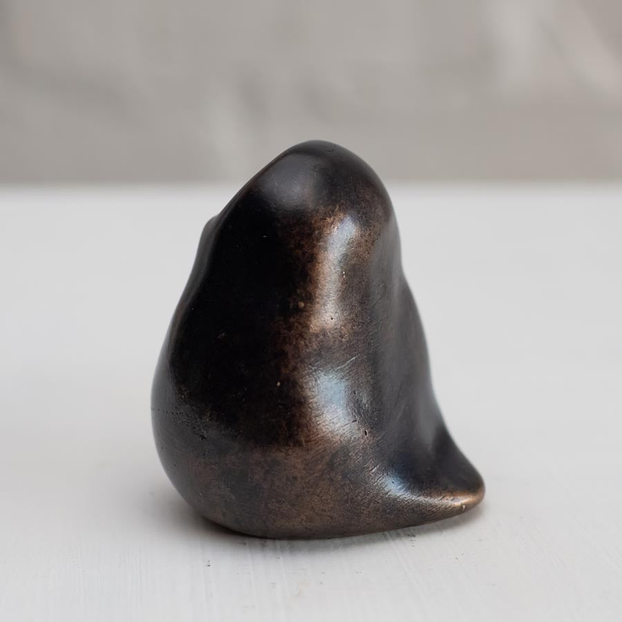 Small smooth bronze owl sculpture on a plain background side view