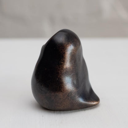 Small smooth bronze owl sculpture on a plain background side view