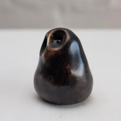 Small smooth bronze owl sculpture on a plain background - side view