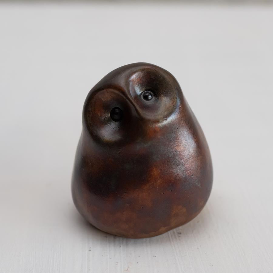 Brown coloured bronze owl sculpture against a white background