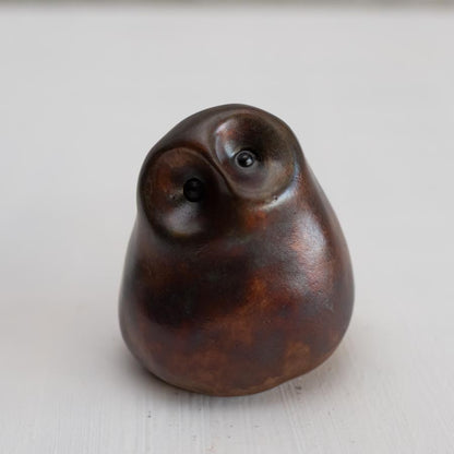 Brown coloured bronze owl sculpture against a white background