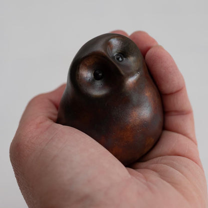 hand holding a Brown coloured bronze owl sculpture against a white background