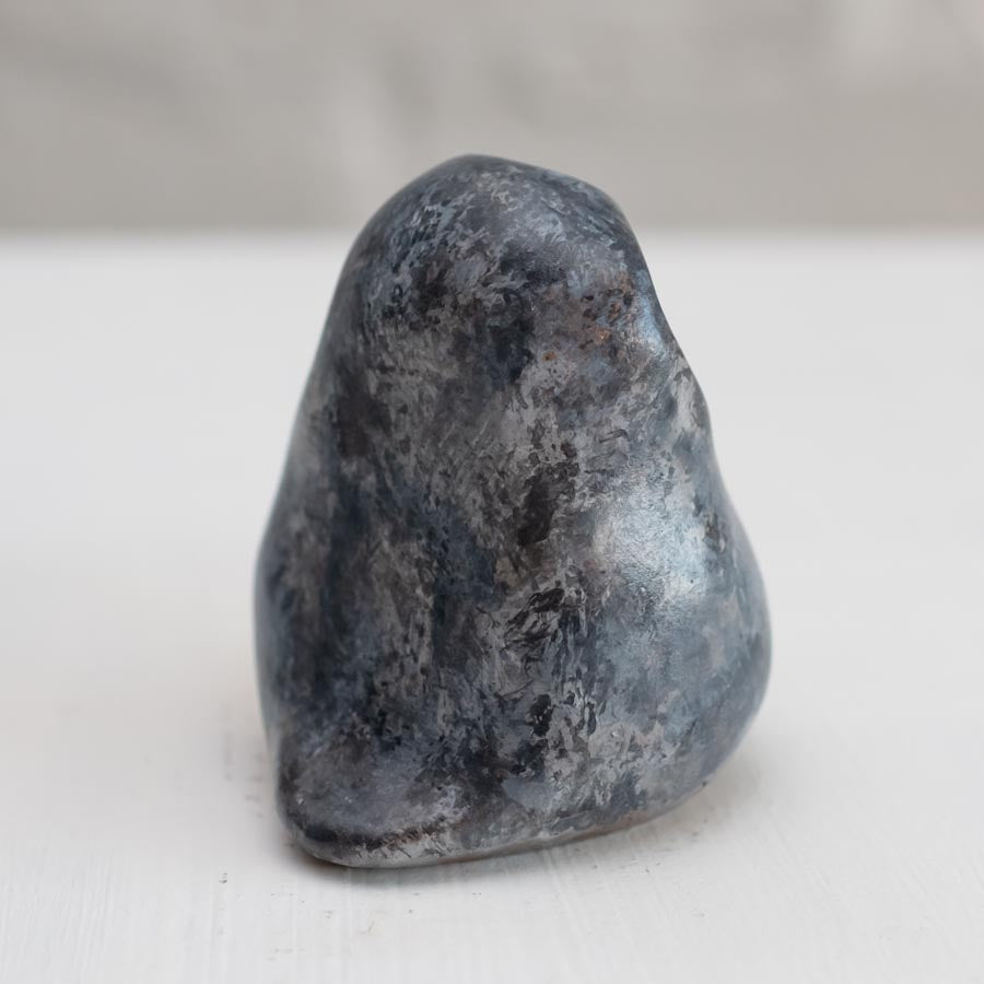 Small grey coloured bronze owl sculpture against a white background - rear view