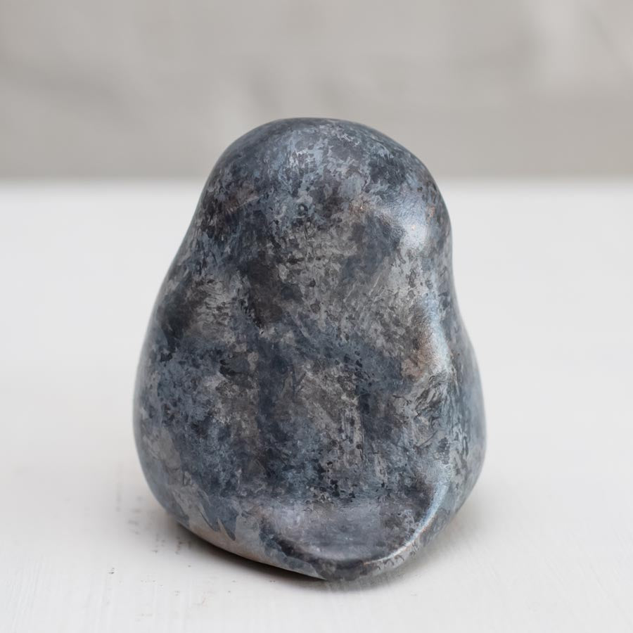 Small grey coloured bronze owl sculpture against a white background - rear view