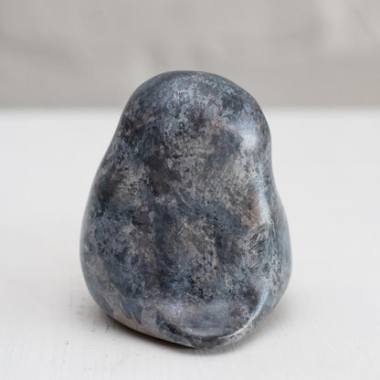 Small grey coloured bronze owl sculpture against a white background - rear view