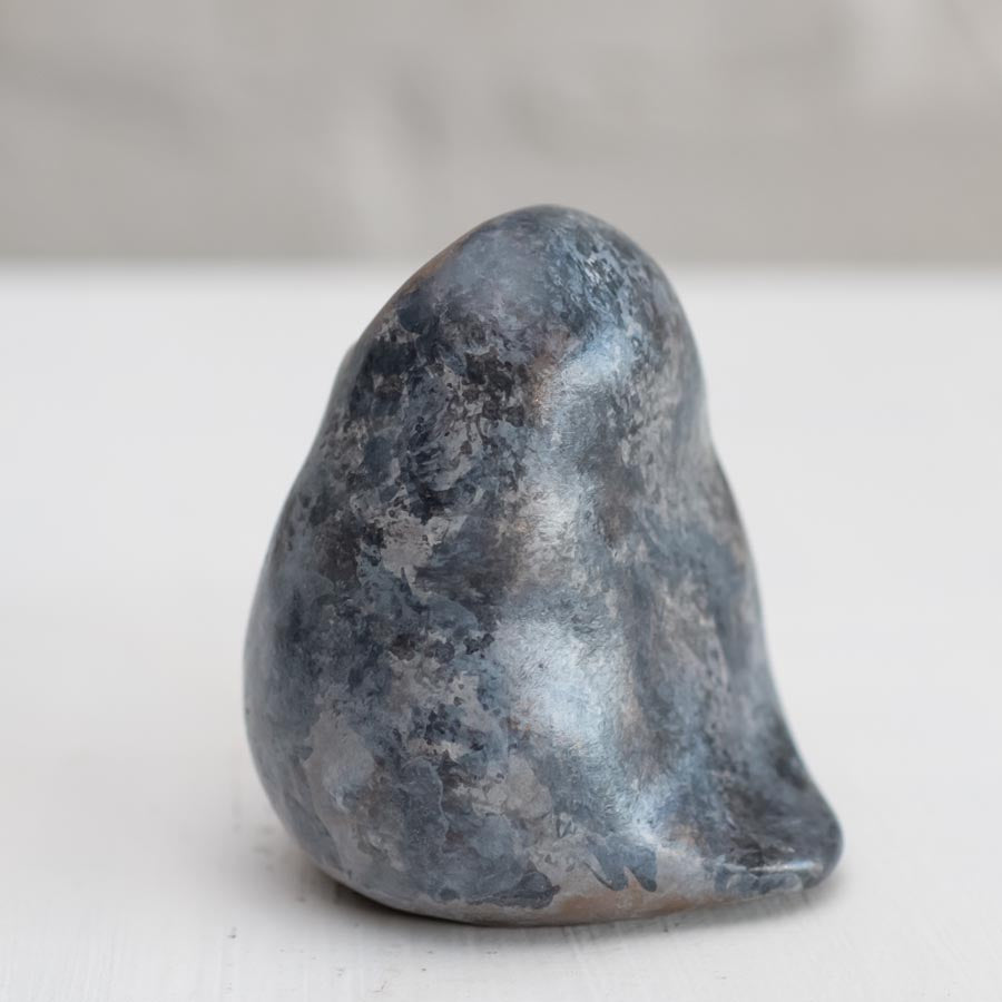 Small grey coloured bronze owl sculpture against a white background - side view