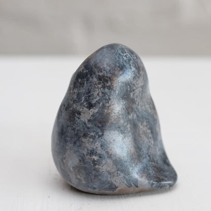 Small grey coloured bronze owl sculpture against a white background - side view