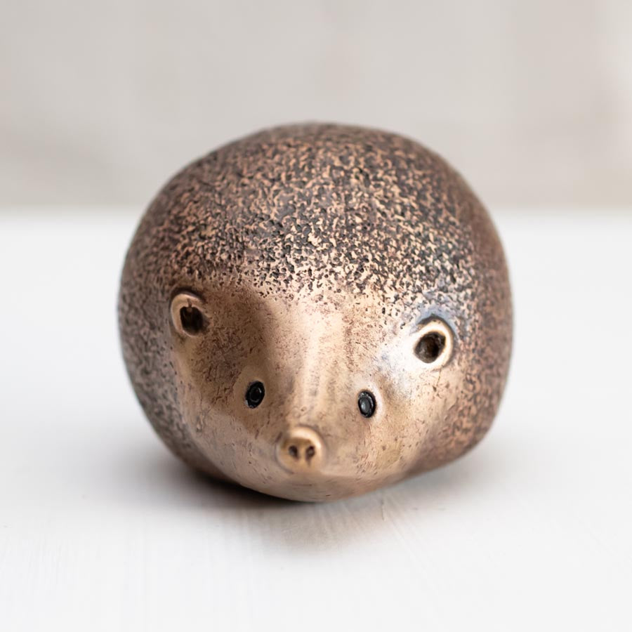 Small bronze hedgehog sculpture on a white background