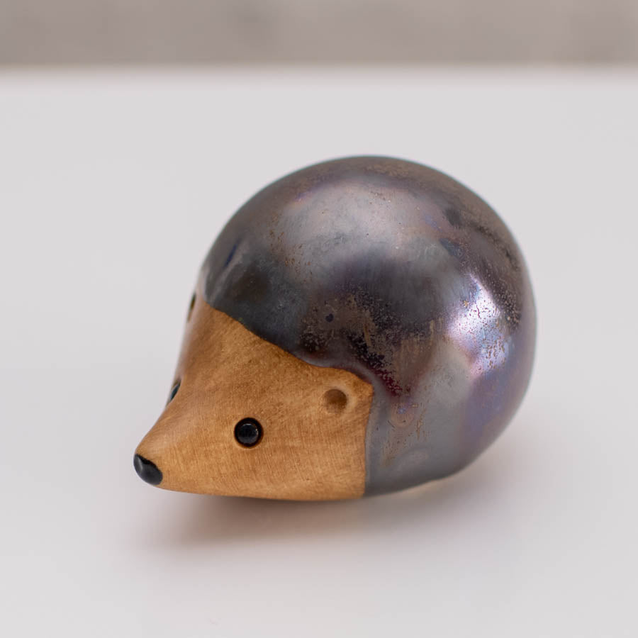 Ceramic hedgehog figurine with a metallic glaze on a white background