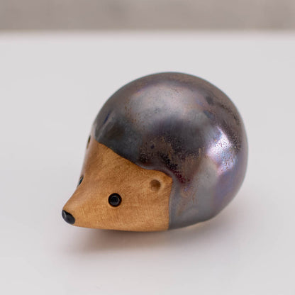 Ceramic hedgehog figurine with a metallic glaze on a white background