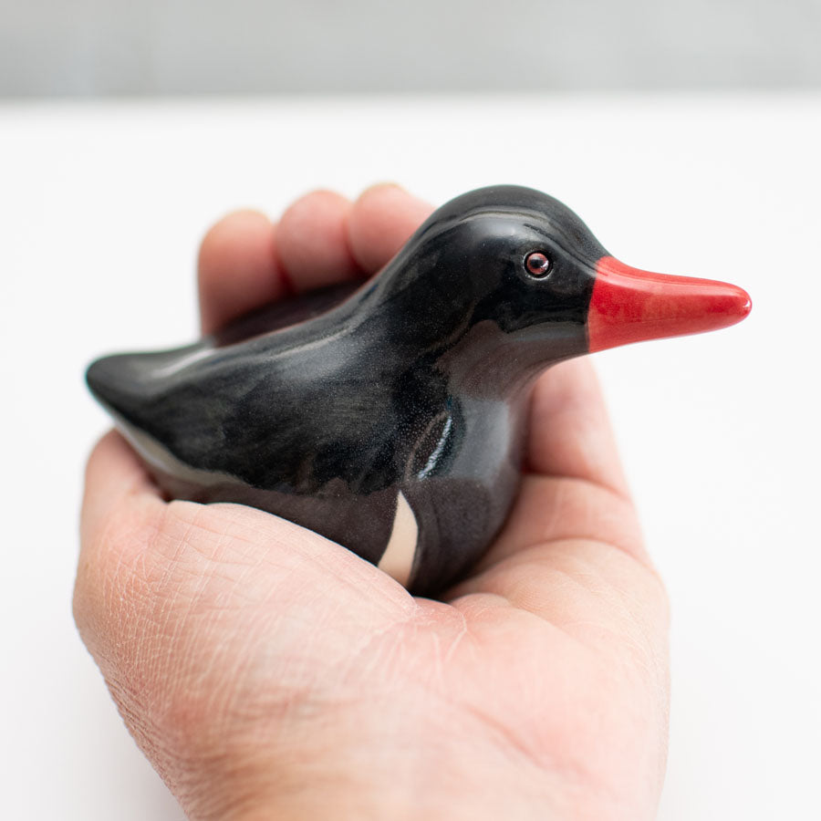 Small ceramic Oystercatcher Sculpture in a hand against a white background