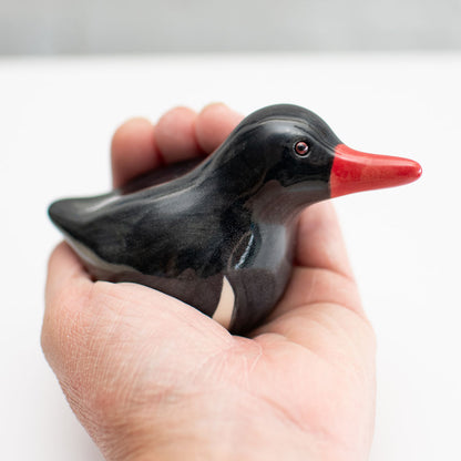 Small ceramic Oystercatcher Sculpture in a hand against a white background