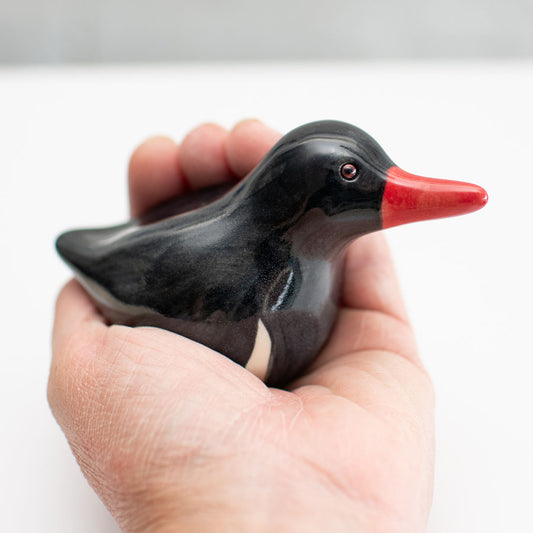 Small ceramic Oystercatcher Sculpture in a hand against a white background