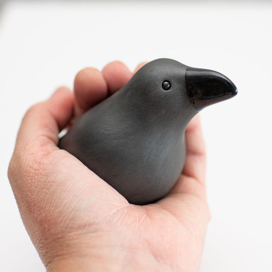 Small ceramic Raven sculpture in a hand