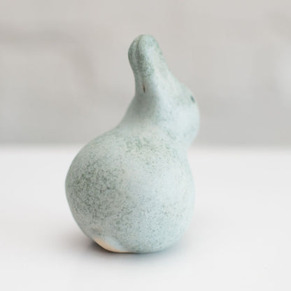 A small grey ceramic bunny sculpture against a grey background