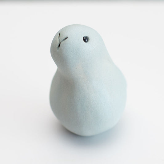 A small grey ceramic bunny sculpture against a grey background