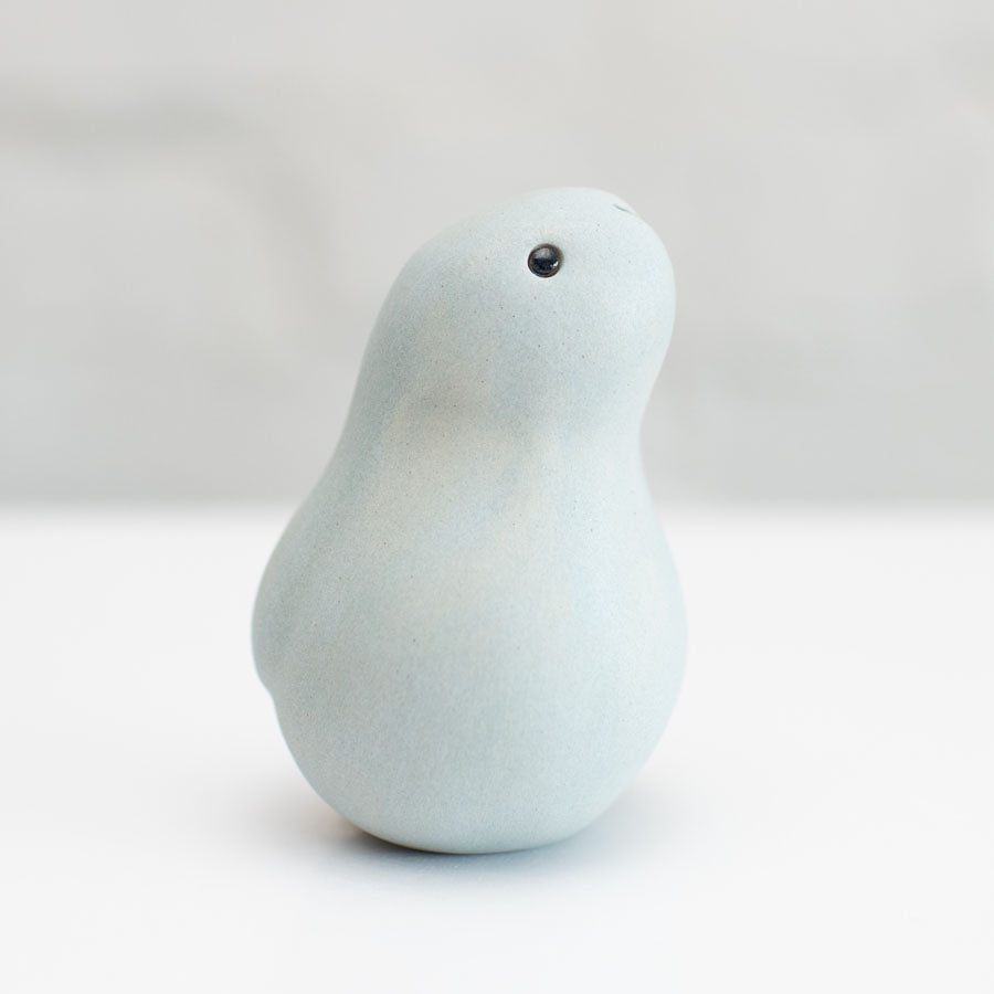 A small grey ceramic bunny sculpture against a grey background
