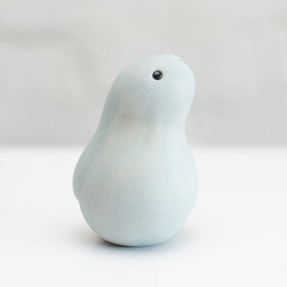 A small grey ceramic bunny sculpture against a grey background
