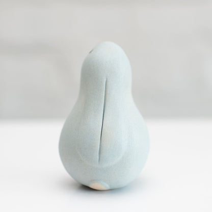 A small grey ceramic bunny sculpture against a grey background