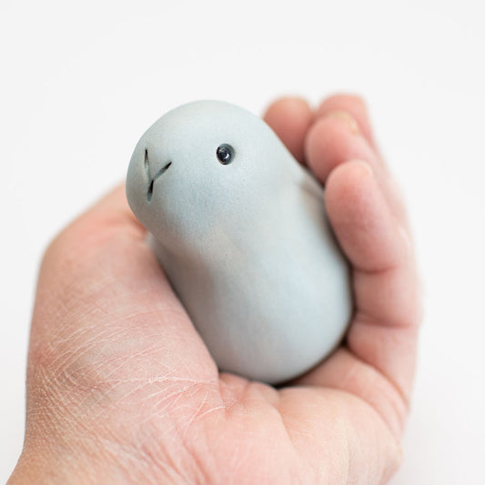 A small grey ceramic bunny sculpture in a hand