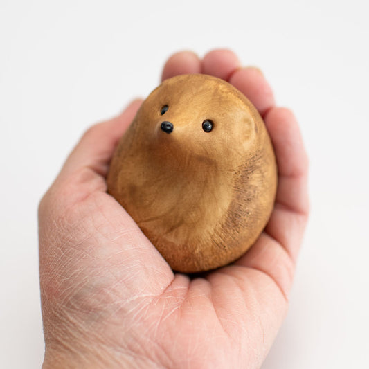 A small brown ceramic hedgehog sculpture in a hand
