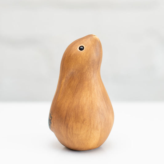 A small ceramic hare sculpture in a chestnut brown colour standing on a white surface against a soft gray background.