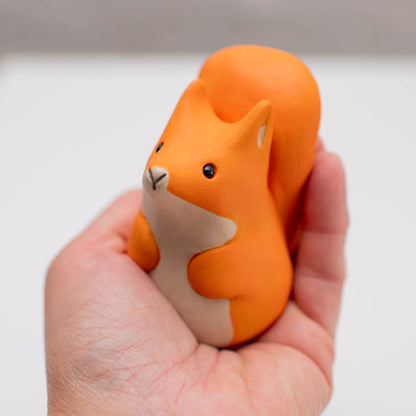 Small ceramic red squirrel sculpture in a hand