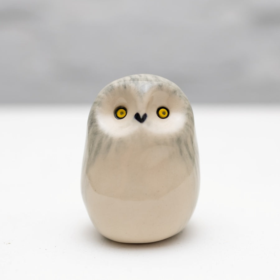 Small ceramic snowy owl sculpture on a white background