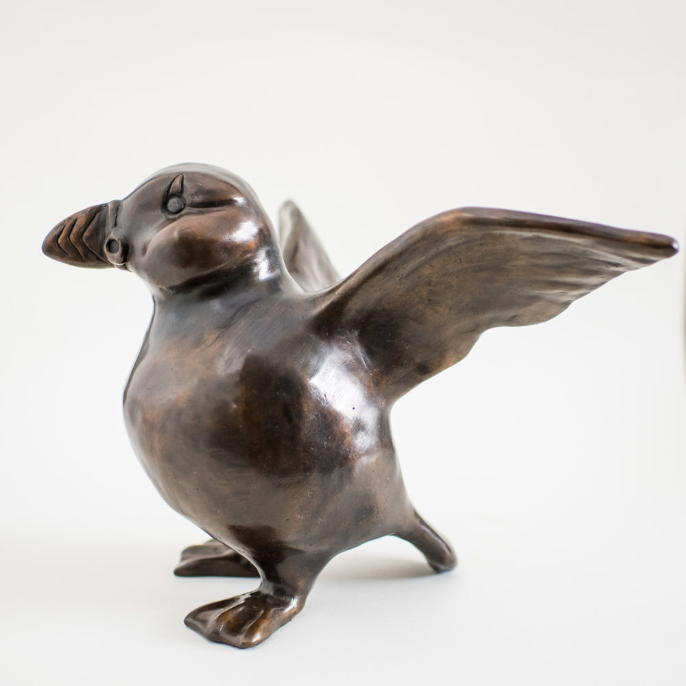 A bronze sculpture of a standing Puffin in a traditional brown bronze patina. The surfaces are smooth and he has character