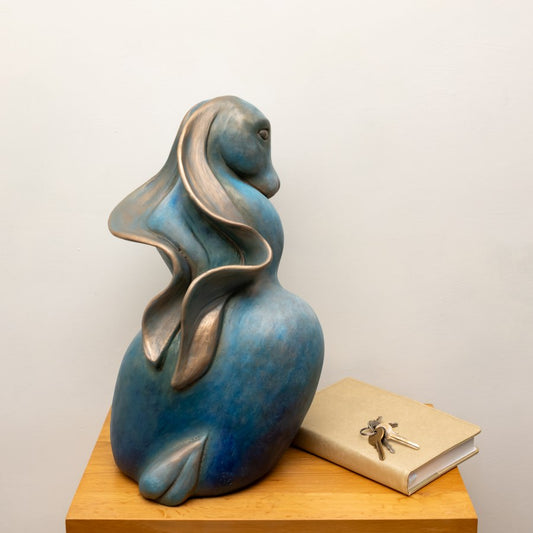 Divine Feminine Power - Bronze Hare Sculpture, blue and bronze, on a wooden surface next to a book and keys