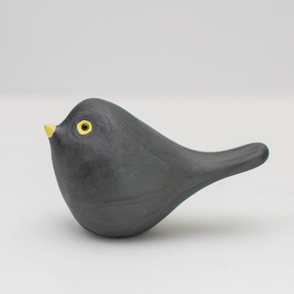 Small ceramic blackbird collectable sculpture on a plain background