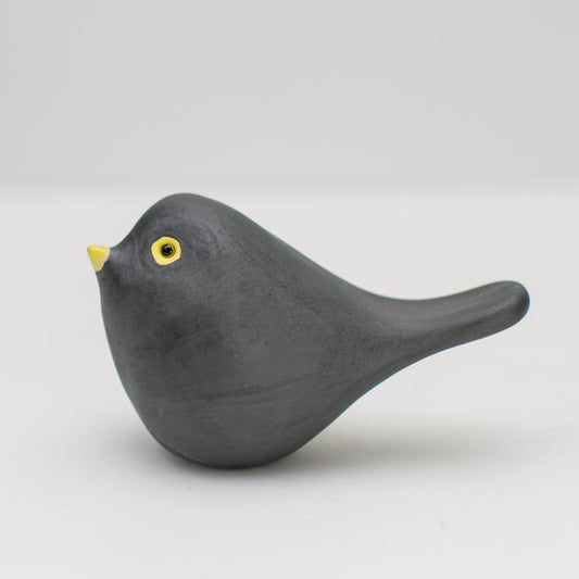 Small ceramic blackbird collectable sculpture on a plain background