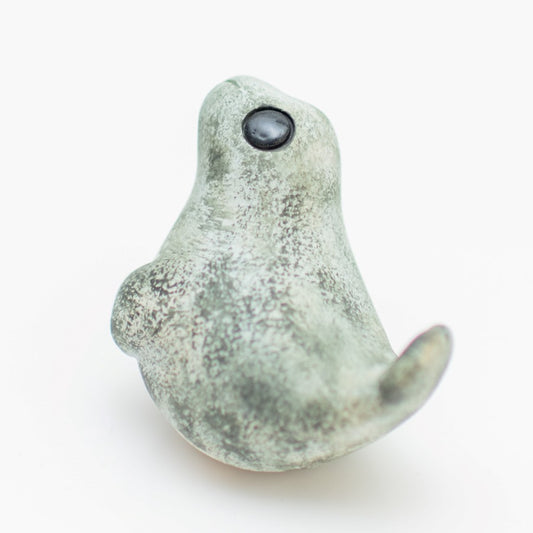 Ceramic Grey Seal Pup Sculpture, light grey with dark speckles, black eye, facing left on white background