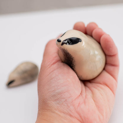 A small badger sculpture in a hand against a white background