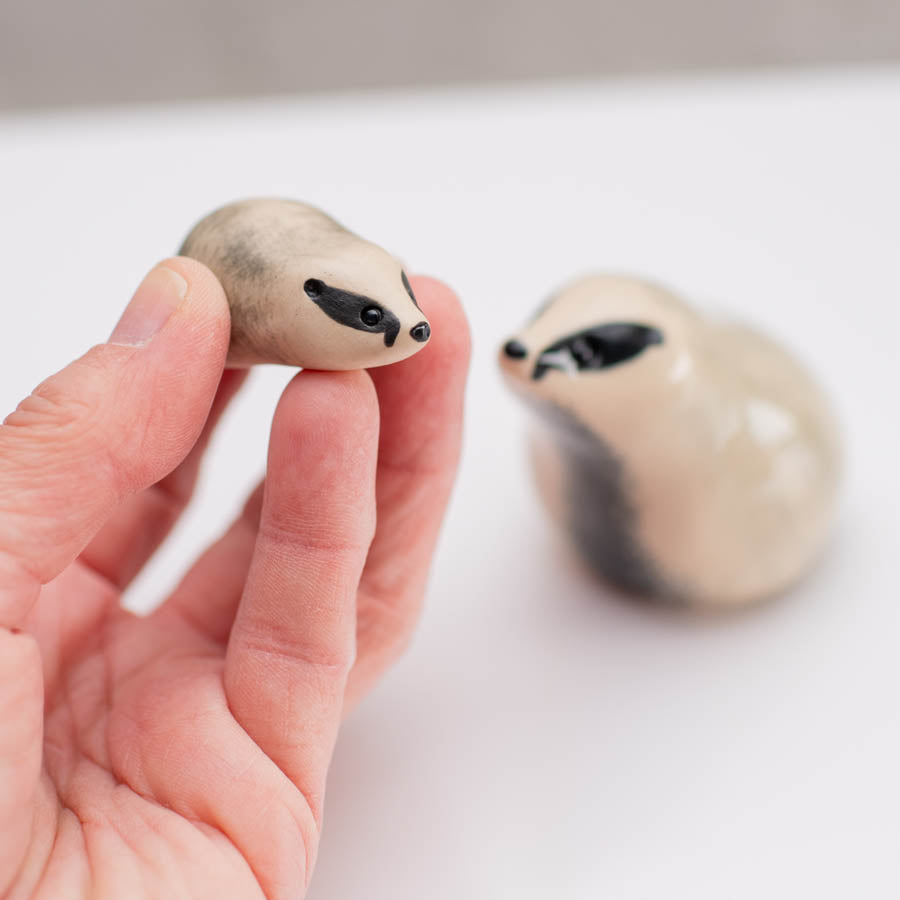 A small badger sculpture in a hand against a white background