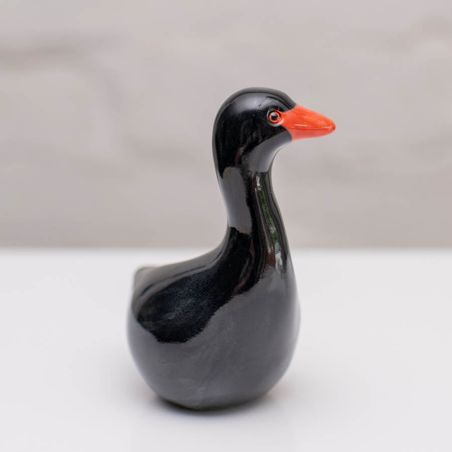 Small ceramic black Swan sculpture against a white background