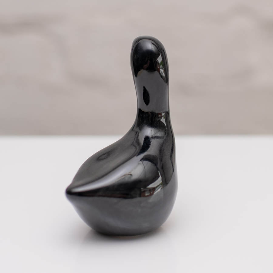 Small ceramic black Swan sculpture against a white background