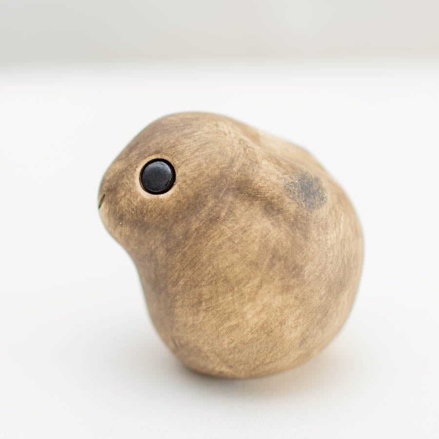 Small ceramic Leveret Sculpture, light brown with a black eye, facing left on a white background