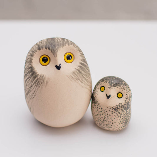 Two hand-painted owl figurines, one large and one small, styled like natural river stones with detailed feather patterns, yellow eyes, and black beaks on a clean white surface.