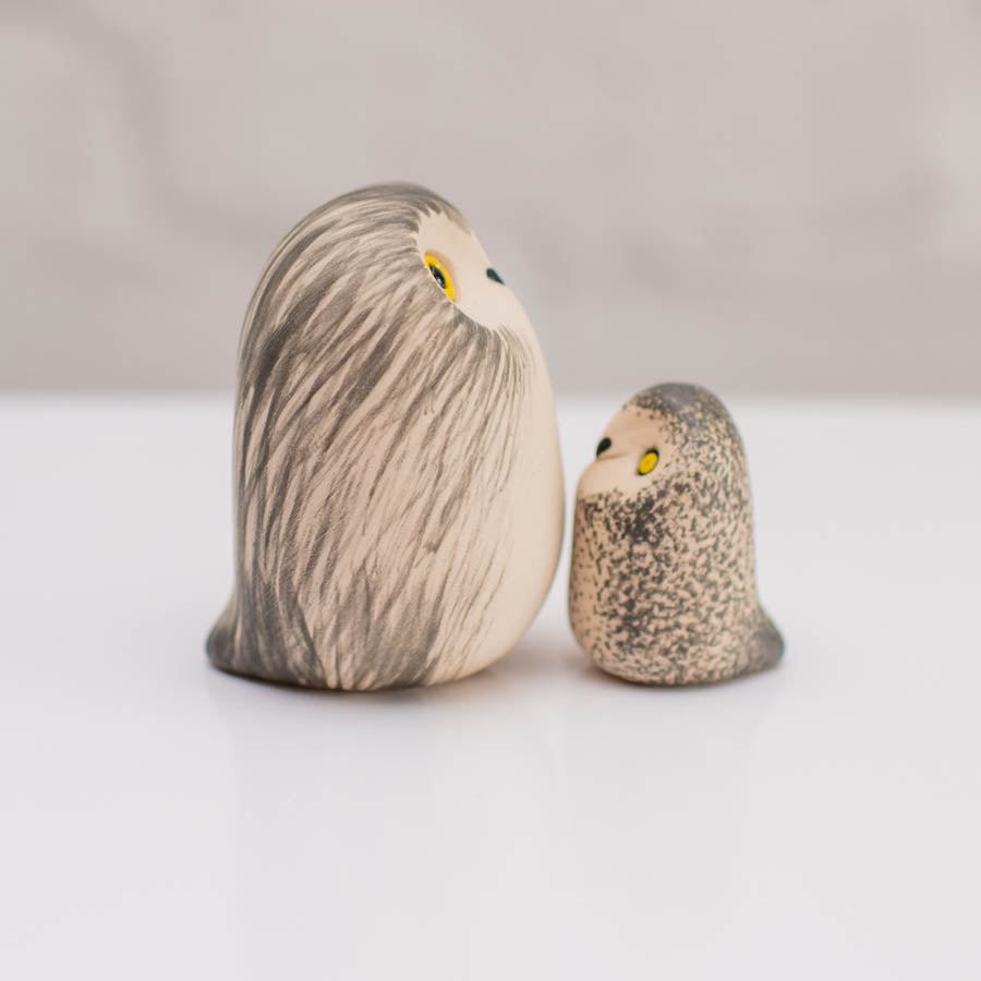 Two hand-painted owl figurines, one large and one small, styled like natural river stones with detailed feather patterns, yellow eyes, and black beaks on a clean white surface.