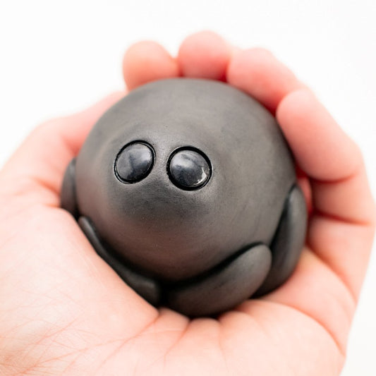 Small black ceramic spider sculpture held in a hand