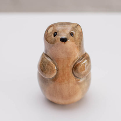 A small ceramic glossy stoat sculpture against a grey backdrop
