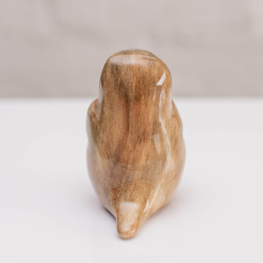 A small ceramic stoat sculpture against a grey backdrop