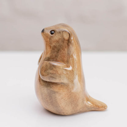 A small ceramic stoat sculpture against a grey backdrop