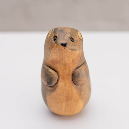 A small ceramic stoat sculpture against a grey backdrop