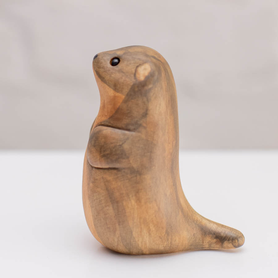 A small ceramic stoat sculpture against a grey backdrop