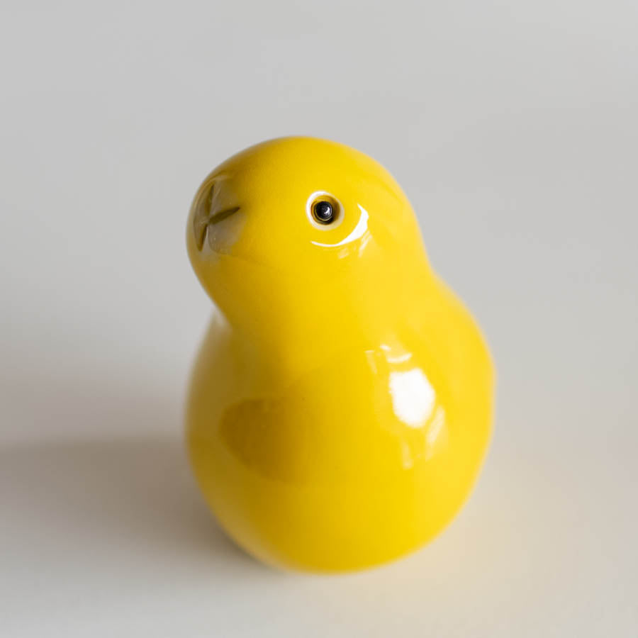 A glossy yellow bunny sculpture standing on a light gray background.
