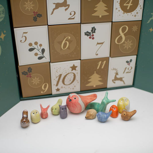 Advent calendar with a group of small ceramic critters gathered around to show what's inside the calendar