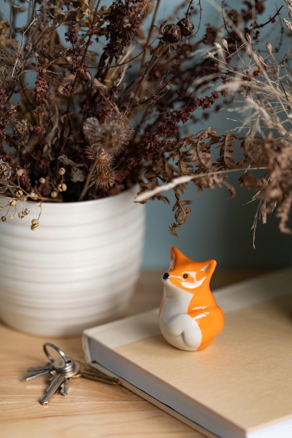 Small fox figurine on a book with dried plants in the background